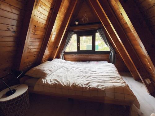 a bed in a wooden room with a window at Domek Letniskowy Dario in Ińsko
