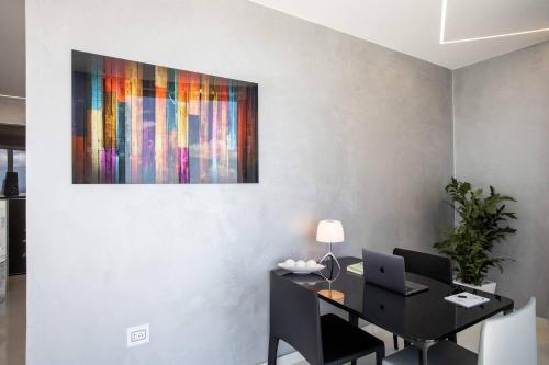a desk with a laptop and a painting on a wall at Serenity Penthouse - The Pinnacle of Luxury in Maho Reef