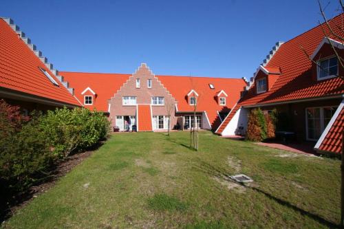 une rangée de maisons avec des toits rouges et une cour dans l'établissement HP Touristik - Seepark Burhave 7, à Butjadingen