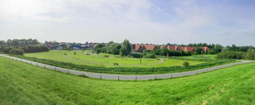 un grand champ herbeux avec une route courbe dans l'établissement HP Touristik - Seepark Burhave 7, à Butjadingen