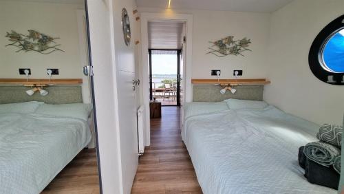 a bedroom with two beds and a hallway with a window at Hausboot Aava in Schleswig
