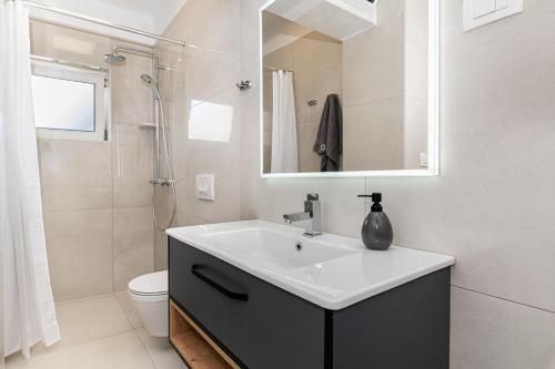 a white bathroom with a sink and a shower at Holiday Home Quadro Rabac in Rabac
