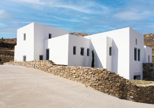 a row of white buildings with a stone wall at Cape Ftelia in Elia