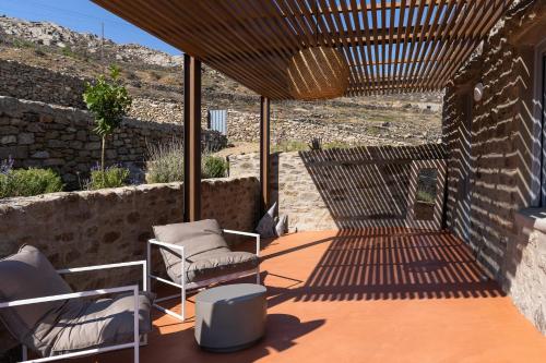 a patio with two chairs and a table and a wall at Cape Ftelia in Elia