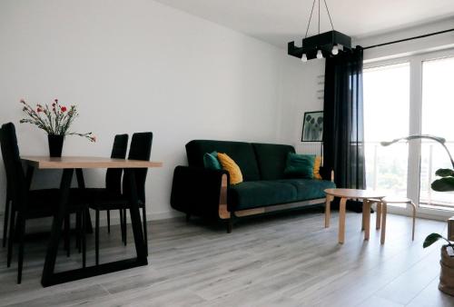 a living room with a green couch and a table at Apartament Tramwajowa 17B in Łódź