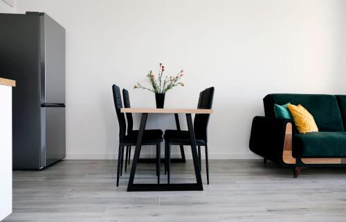 a dining room table with chairs and a vase with flowers at Apartament Tramwajowa 17B in Łódź