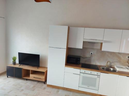 Il comprend une cuisine avec des placards blancs, un évier et une télévision. dans l'établissement Apartman Bartol, à Skradin