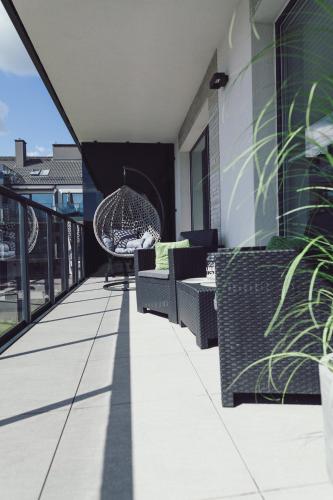 a balcony with wicker chairs and tables on a building at Apartament Rejs in Ostróda