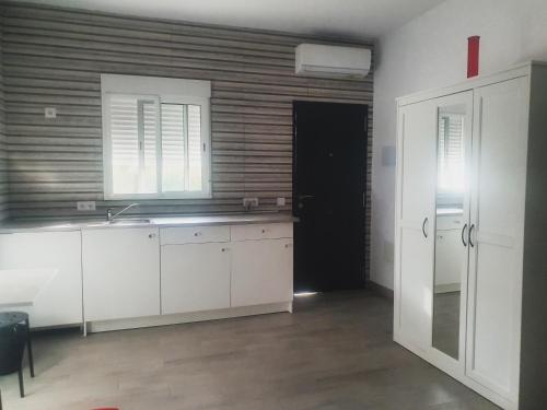 a kitchen with white cabinets and a sink and a door at Bungalows en La Oliva Vejer in El Soto