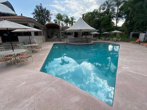 a swimming pool in a patio with tables and umbrellas at Hotel Marjaba in Cuernavaca