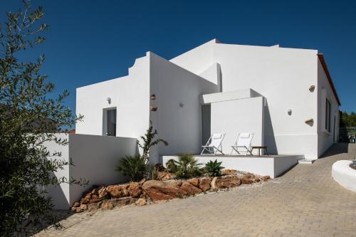 een wit gebouw met twee stoelen ervoor bij Casa Monte dos Entrudos in Almancil