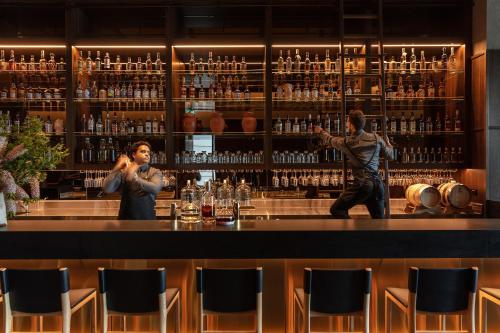 two people standing at a bar in a room with alcohol at Next Hotel Melbourne in Melbourne