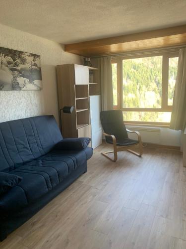 sala de estar con sofá azul y silla en Appartement dans résidence avec piscine, en Saint-Jean-dʼAulps