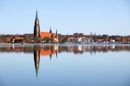 a reflection of a town in the water with a church at Hausboot Hilja in Schleswig