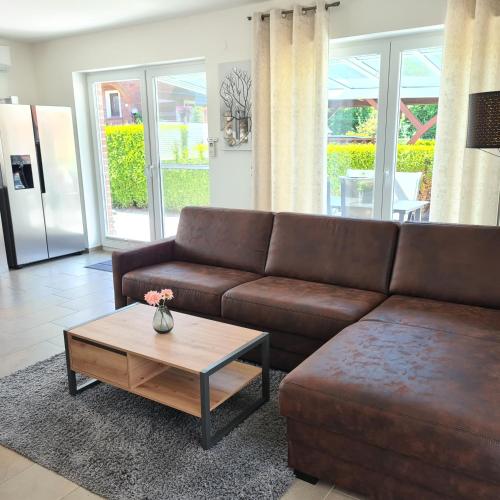 a living room with a brown couch and a coffee table at Haus Hobbingshof Greetsiel in Greetsiel