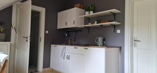 una cocina con armarios blancos en una habitación en Klimatyczny apartament w Oliwie, en Gdansk