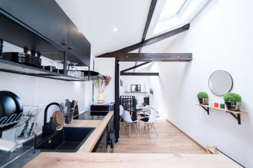 une cuisine avec des comptoirs noirs, un évier et une table dans l'établissement La Luna - Élégante Maison de Standing avec extérieur - 25 min de Paris, à Andrésy