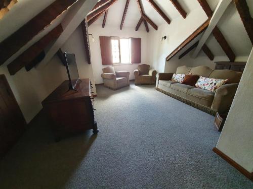 a living room with couches and chairs in a attic at Casa do Cruzeiro in Aguiar da Beira