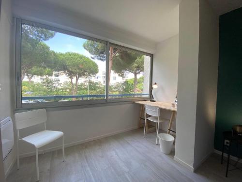 une pièce avec un bureau et une grande fenêtre dans l'établissement LE ESTELLA APPART - PARKING WIFI au CALME 2 Min PLAGES - Résid LE RAYOL - TOP PROS SERVICESConciergerie La Grande Motte, à La Grande Motte