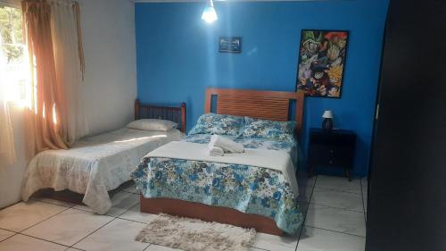 een slaapkamer met 2 bedden en blauwe muren bij ACONCHEGO DE CANELA/RS in Canela