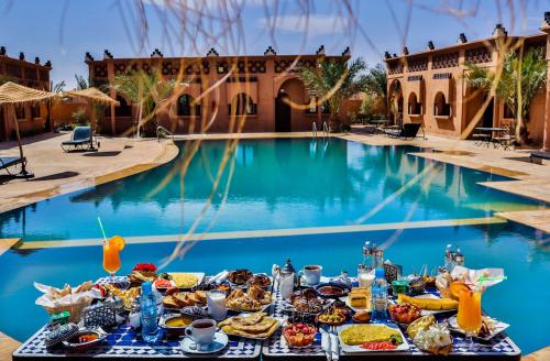 a table of food next to a swimming pool at Residence Touristique Merzouga in Merzouga