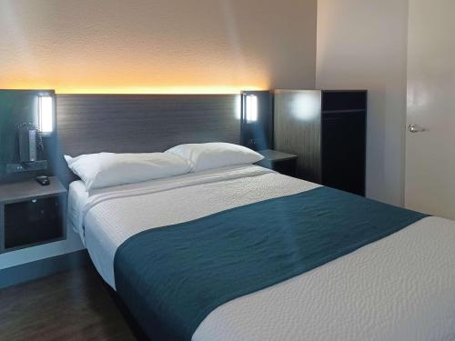 a bedroom with a large bed with a blue blanket at Motel 6-Fresno, CA - Blackstone North in Fresno