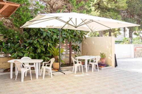 a white table and chairs under an umbrella at La Curte dellu Pippi Niuru in Lecce