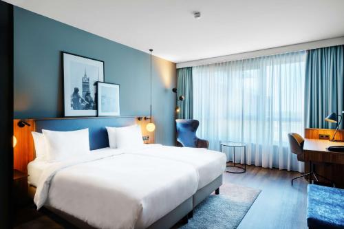 um quarto de hotel com uma grande cama branca e uma secretária em Radisson Blu Hotel Rostock em Rostock