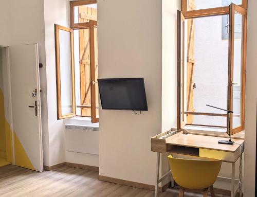 une pièce avec un bureau et une télévision sur un mur dans l'établissement Modern loft down town, à Foix
