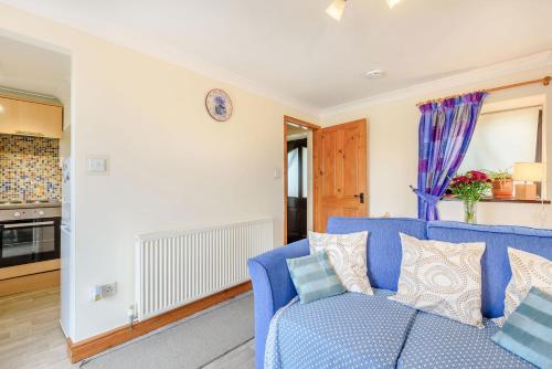 a living room with a blue couch and a kitchen at Ystabl - Stable in Llanddulas