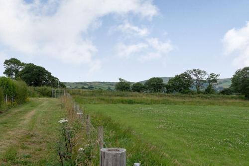 a field with a fence and a dirt road at Ystabl - Stable in Llanddulas