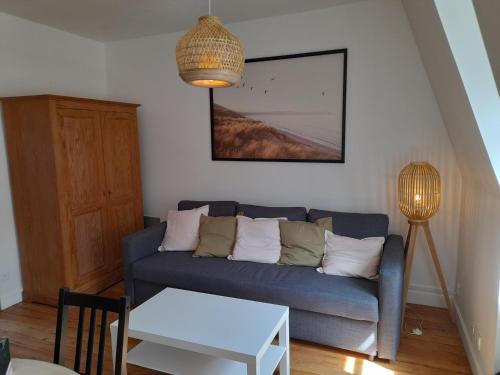 uma sala de estar com um sofá azul e uma mesa em Charmante Villa plein SUD 50m de la plage - Balcon vue latérale sur Mer - équipée de la Fibre, Wifi, internet em Mers-les-Bains