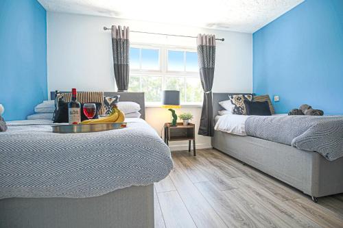 1 dormitorio azul con 2 camas y ventana en Delightful 2 BED APARTMENT for BICESTER OUTLET SHOPPING by Platinum Key Properties en Bicester