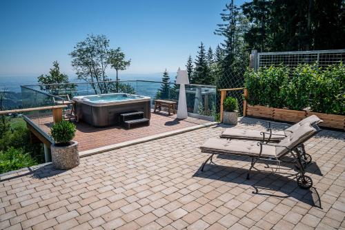 a patio with a hot tub and a table and chairs at Schilcherland Chalet Südsteiermark in Trahütten
