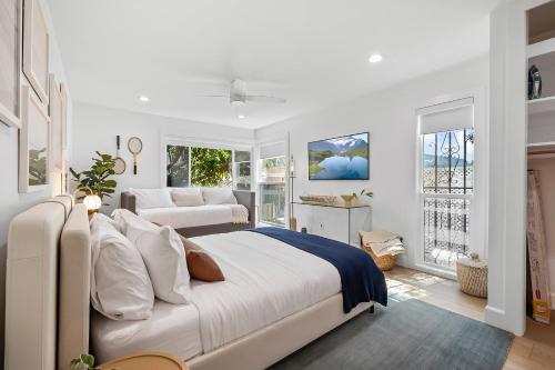 a white bedroom with a large bed and windows at Hideaway Zen in San Diego