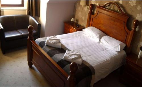 um quarto com uma cama de madeira e uma cadeira em Ban-Car Hotel em Cairness