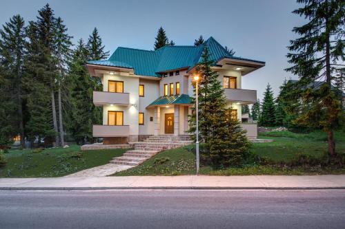 a large house with a green roof at Apartmani Bijelic in Žabljak