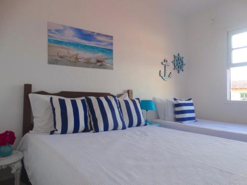 VIVA BUZIOS no Condominio Aqua Marina casa13 في بوزيوس: غرفة نوم مع سرير ووسائد زرقاء وبيضاء