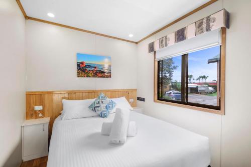 a bedroom with a white bed and a window at Moruya Holiday Park in Moruya