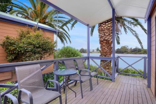 a porch with chairs and a table and a palm tree at Moruya Holiday Park in Moruya