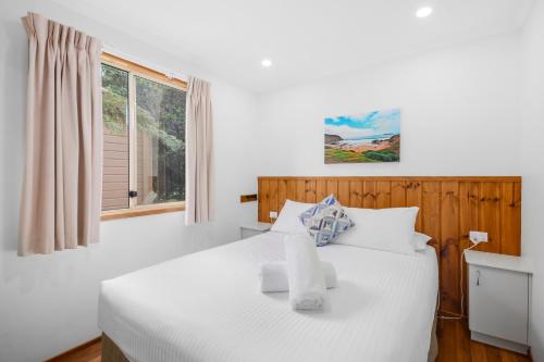 a bedroom with a white bed and a window at Moruya Holiday Park in Moruya