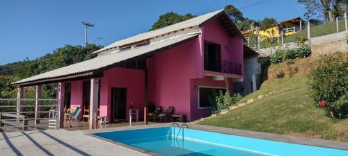 a pink house with a swimming pool in front of it at Casa em São Roque Com belissima vista. in São Roque