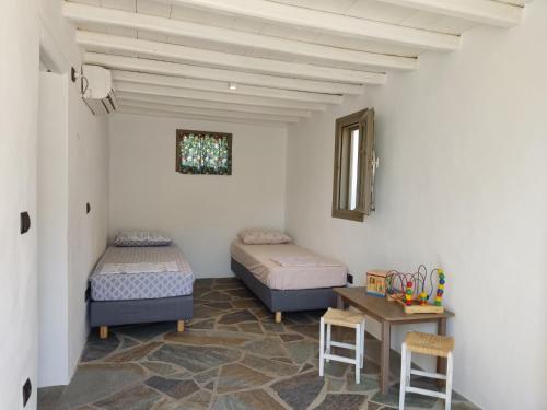 two beds in a room with a table and chairs at Melia Sifnos House in Platis Yialos Sifnos