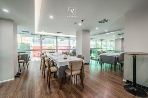 a dining room with tables and chairs and windows at VH Eurostar Tirana Hotel Congress & Tirana Spa in Tirana