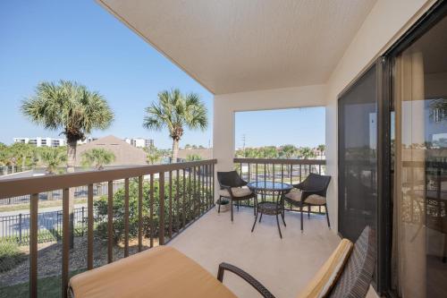 a balcony with a table and chairs and palm trees at Ocean Village Club D23 in Saint Augustine