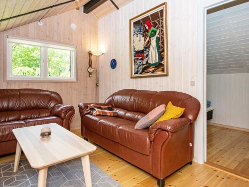 ein Wohnzimmer mit einem braunen Ledersofa und einem Tisch in der Unterkunft 6 person holiday home in Ansager in Ansager