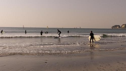 a group of people standing on the beach with surfboards at 翡翠-Jade- in Kamakura