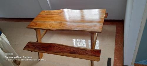 uma mesa de madeira com um banco sentado no chão em Homestay Sultan Ramadhan Aur Kuning Bukittinggi em Bukittinggi