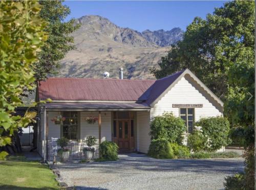 a small white house with mountains in the background at Old School House in Queenstown