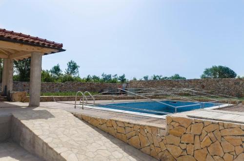 a swimming pool with a stone retaining wall and a stone wall at Apartments Dujo in Rupe